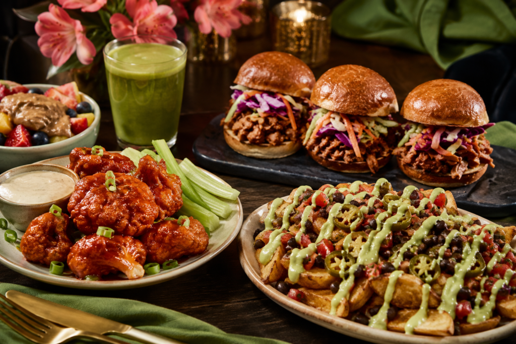 plant-based-comfort-food-swaps-cravings Plant-based comfort food swaps with cauliflower wings, BBQ jackfruit sliders, loaded potatoes, fruit, and smoothie.