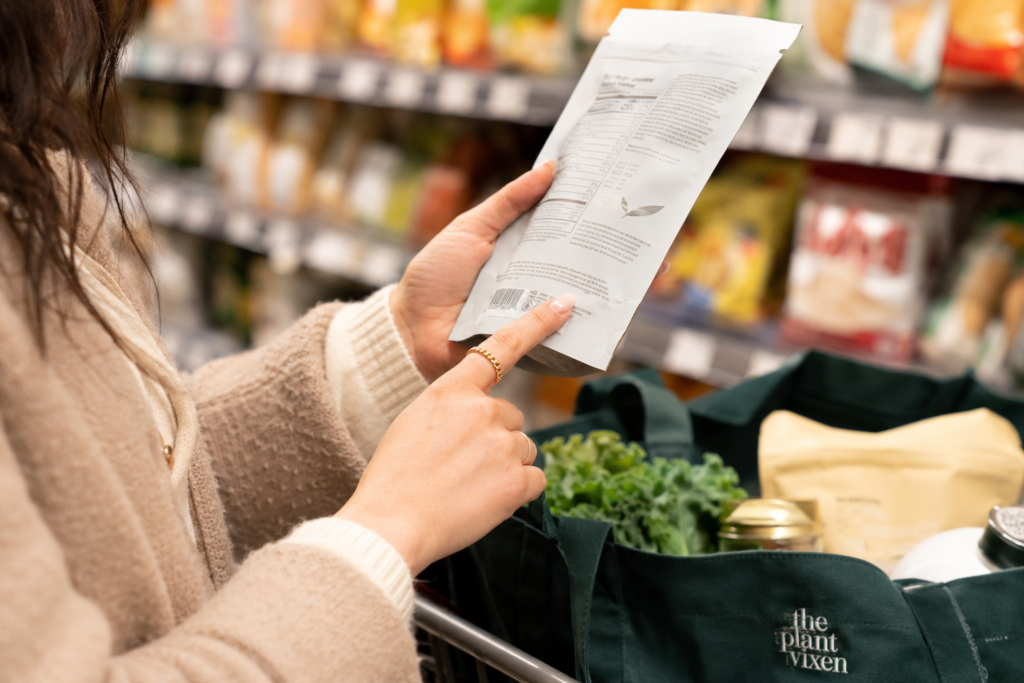 Hands checking the allergen statement on a packaged food label for milk ingredients.