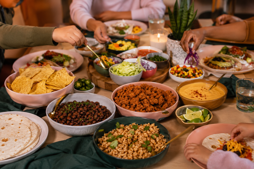   Family plant-based taco night with beans, rice, plant-based crumbles, salsa, avocado, dairy-free queso, chips, and tortillas.