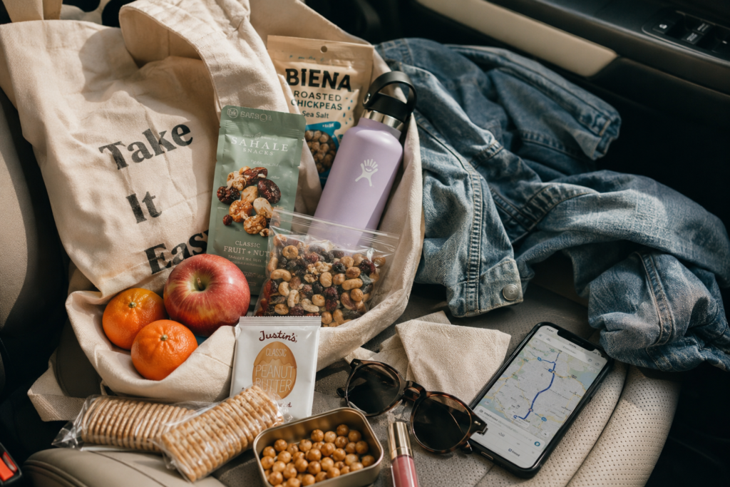  Plant-based travel snack bag with fruit, trail mix, crackers, roasted chickpeas, and water.